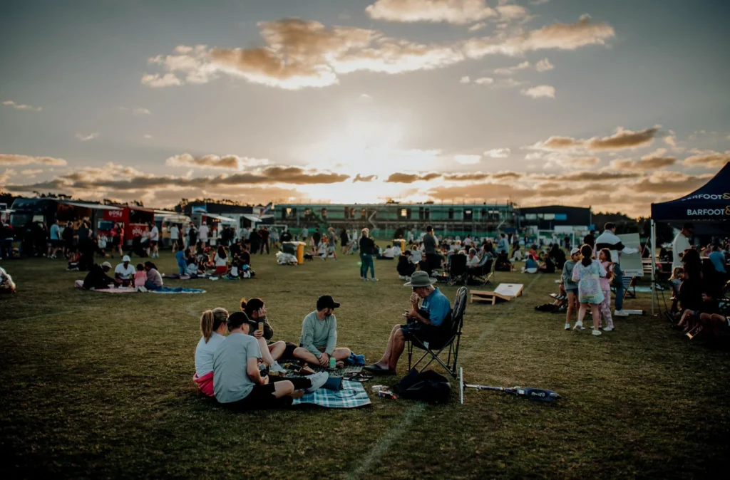 Gruppo di persone mangia e beve ad un picnic in un campo da calcio